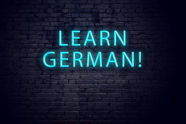 Tuğla duvar ve yazıtlı neon işareti. Almanca öğrenme kavramı