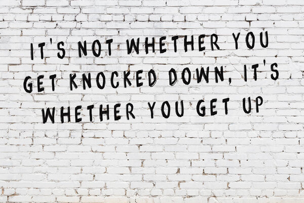 White brick wall with painted black motivational quote inscription