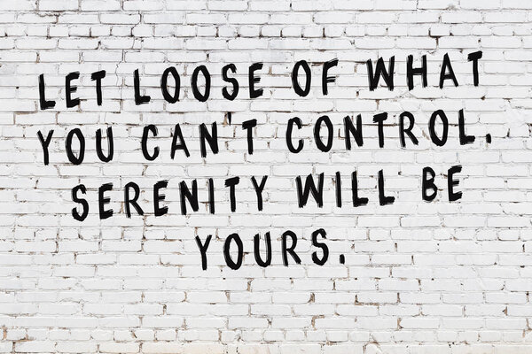 Стена из белого кирпича с раскрашенной черной мотивационной надписью
