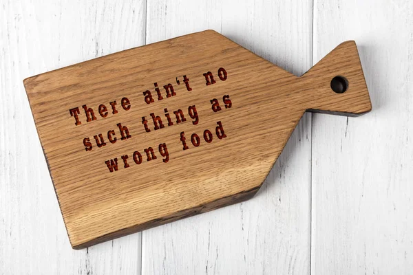 Houten snijplank met wijze inscriptie over voedsel — Stockfoto