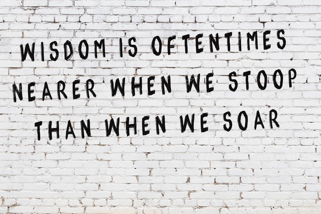 White brick wall with painted black motivational quote inscription