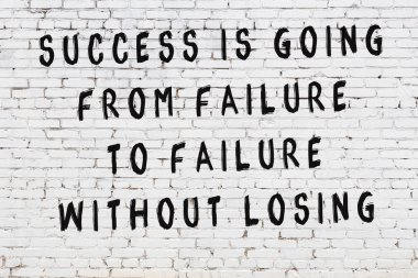 Beyaz tuğla duvar arkaplanına siyah düşünceli bir yazı.