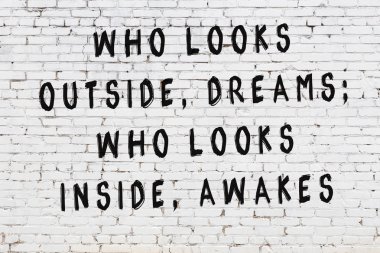 Beyaz tuğla duvar arkaplanına siyah düşünceli bir yazı.