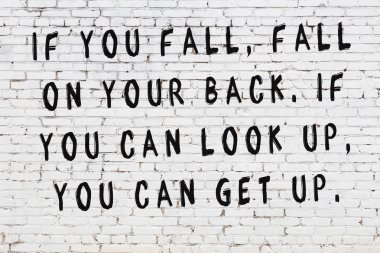 Beyaz tuğla duvar arkaplanına siyah düşünceli bir yazı.