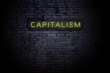 Neon yazıtlı kapitalizmile vurgulanmış tuğla duvar
