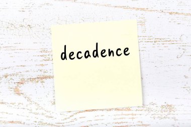 Tahta duvardaki sarı yapışkan notada el yazısıyla yazılmış kelime bozulması var.