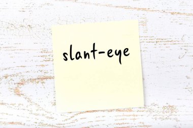 Tahta duvarda el yazısıyla yazılmış sarı yapışkan bir not var.