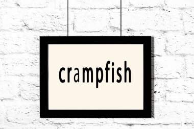 Beyaz tuğla duvarda asılı siyah çerçeve ve karides.