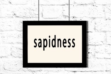 Beyaz tuğla duvarda asılı siyah çerçeve.