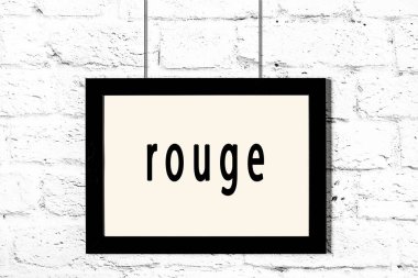 Beyaz tuğla duvarda asılı siyah çerçeve ve allık.