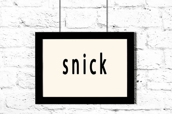 Quadro preto pendurado na parede de tijolo branco com snick inscrição — Fotografia de Stock