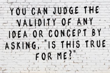 Beyaz tuğla duvara zekice alıntılar yazılı siyah bir yazı.