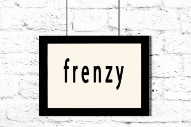 Beyaz tuğla duvarda asılı duran siyah çerçeve.