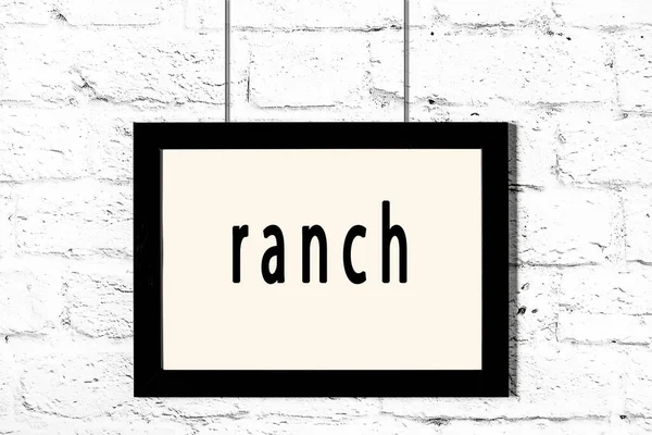 Černý rám zavěšený na zdi z bílých cihel s nápisem ranč — Stock fotografie