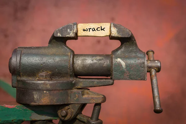 Ferramenta de aperto de vício apertando uma prancha com a palavra wrack — Fotografia de Stock