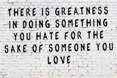 Beyaz tuğla duvara zekice alıntılar yazılı siyah bir yazı.