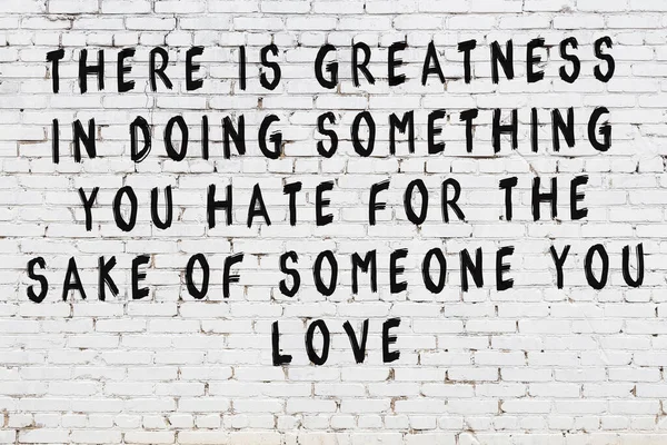 Beyaz tuğla duvara zekice alıntılar yazılı siyah bir yazı.