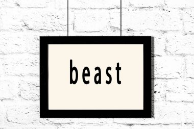 Beyaz tuğla duvarda asılı siyah çerçeve ve yazıt canavarı