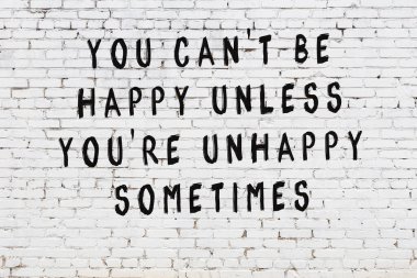 Beyaz tuğla duvara zekice alıntılar yazılı siyah bir yazı.