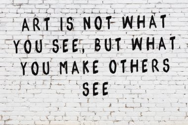 Beyaz tuğla duvara zekice alıntılar yazılı siyah bir yazı.