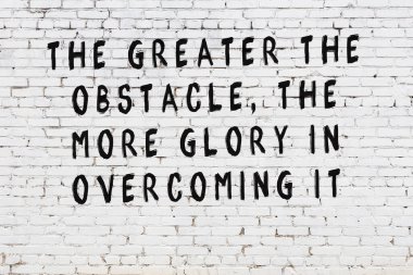 Beyaz tuğla duvara zekice alıntılar yazılı siyah bir yazı.