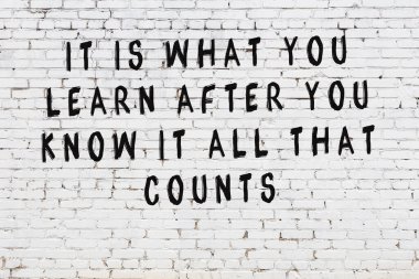 Beyaz tuğla duvar arkaplanına siyah düşünceli bir yazı.