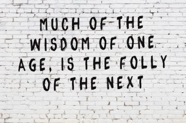 Beyaz tuğla duvara zekice alıntılar yazılı siyah bir yazı.