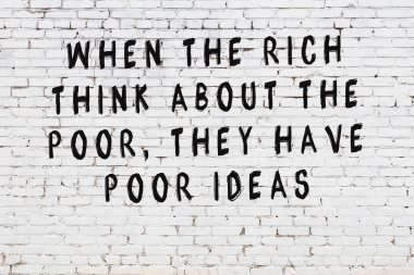 Beyaz tuğla duvar arkaplanına siyah düşünceli bir yazı.