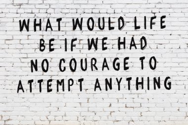 Beyaz tuğla duvara zekice alıntılar yazılı siyah bir yazı.