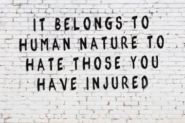 Beyaz tuğla duvara zekice alıntılar yazılı siyah bir yazı.