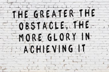 Beyaz tuğla duvara zekice alıntılar yazılı siyah bir yazı.