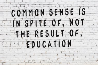 Beyaz tuğla duvara zekice alıntılar yazılı siyah bir yazı.