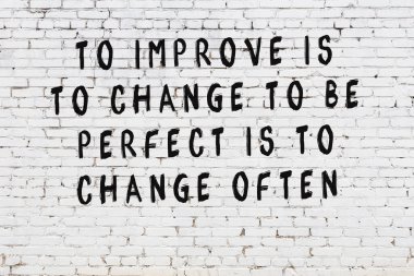 Beyaz tuğla duvar arkaplanına siyah düşünceli bir yazı.