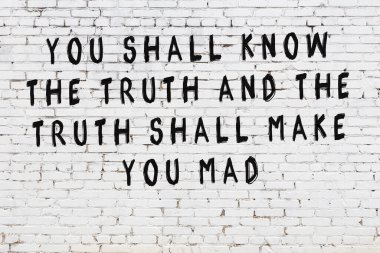 Beyaz tuğla duvara zekice alıntılar yazılı siyah bir yazı.