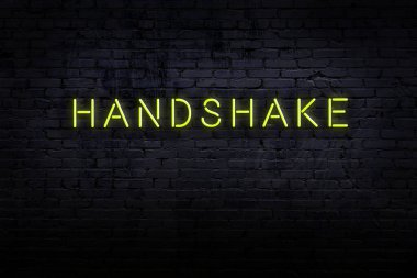 Neon işareti. Duvara karşı kelime tokalaşması. Gece görünümü