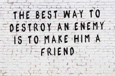 Beyaz tuğla duvara zekice alıntılar yazılı siyah bir yazı.