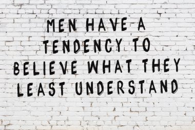 Beyaz tuğla duvar arkaplanına siyah düşünceli bir yazı.