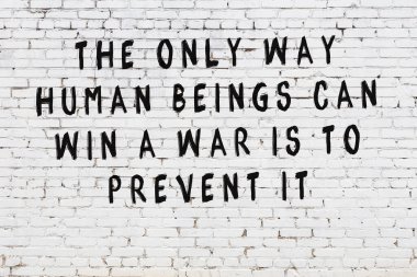 Beyaz tuğla duvar arkaplanına siyah düşünceli bir yazı.