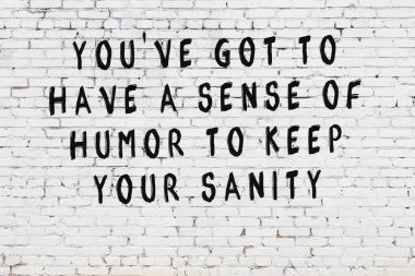 Beyaz tuğla duvara zekice alıntılar yazılı siyah bir yazı.