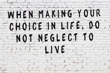 Beyaz tuğla duvara zekice alıntılar yazılı siyah bir yazı.