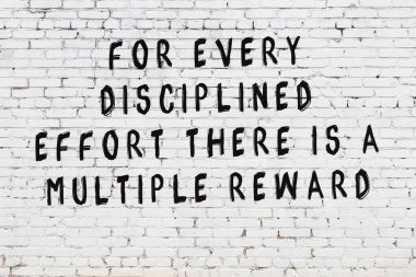 Beyaz tuğla duvara zekice alıntılar yazılı siyah bir yazı.