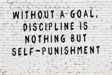 Beyaz tuğla duvara zekice alıntılar yazılı siyah bir yazı.