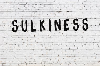 Üzerinde siyah boya ve somurtkan bir yazı olan beyaz duvar.