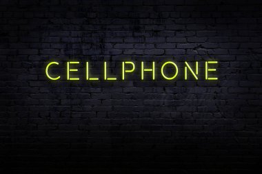 Neon işareti. Cep telefonu tuğladan duvara dayanıyor. Gece görünümü