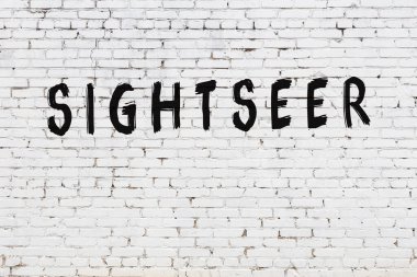 Beyaz tuğla duvara yazı yazan gezgin.