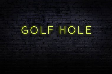 Neon işareti. Kelime golf deliğine karşı tuğla duvar. Gece görünümü