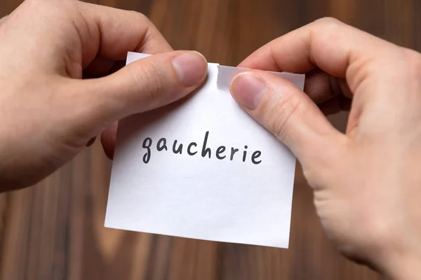 Χέρια ενός ανθρώπου που σχίζει ένα κομμάτι χαρτί με επιγραφή gaucherie — Φωτογραφία Αρχείου