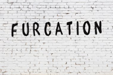 Beyaz tuğla duvara kazınmış bir yazı.