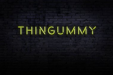 Tuğla duvardaki neon levhanın gece görüşü. Üzerinde yazı zımbırtısı var.