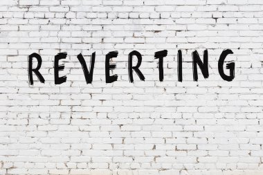 Yazı, beyaz tuğla duvara boyanmış.